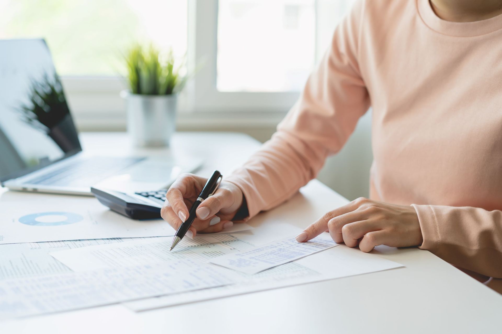 A Woman Is Sitting At A Desk Writing On A Piece Of Paper
