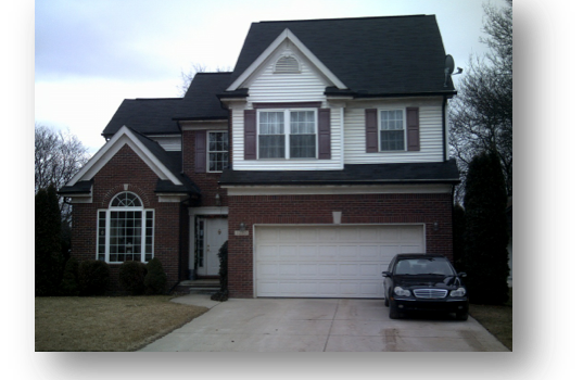 A Black Car Is Parked In Front Of A Large Brick House