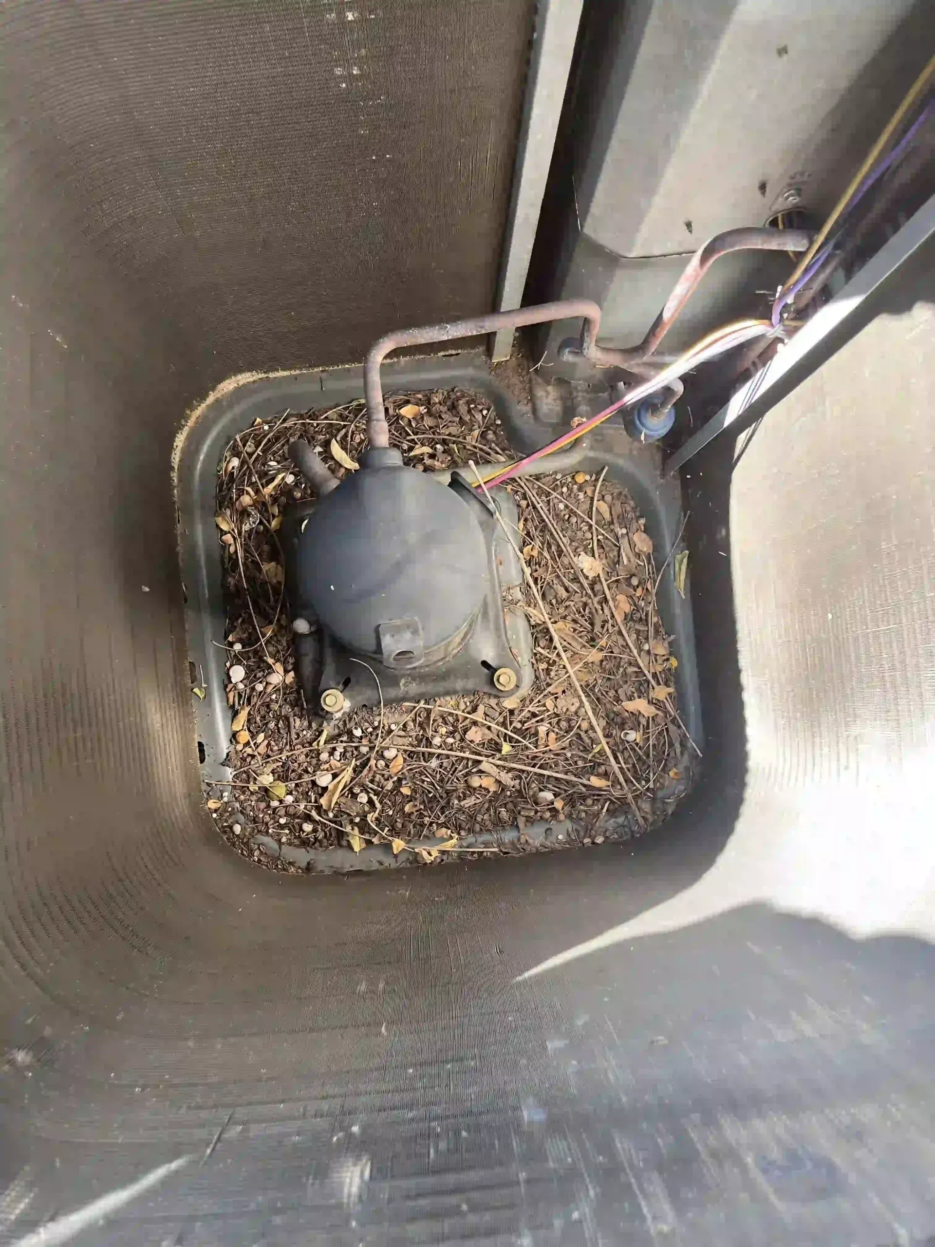 AC unit's interior filled with debris, with a central compressor.