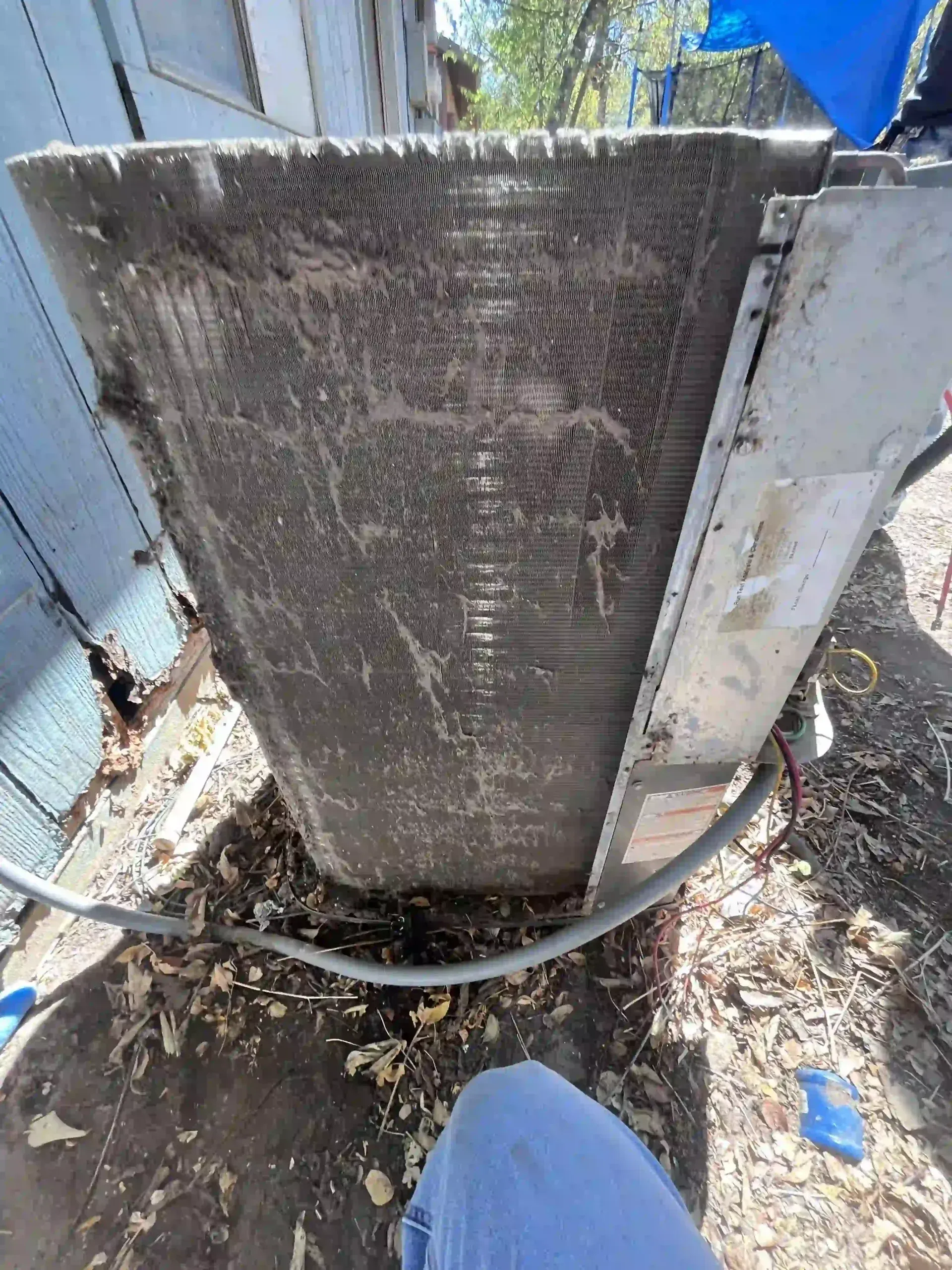 Dirty air conditioner coil; outdoor setting; heavy dust and debris visible.
