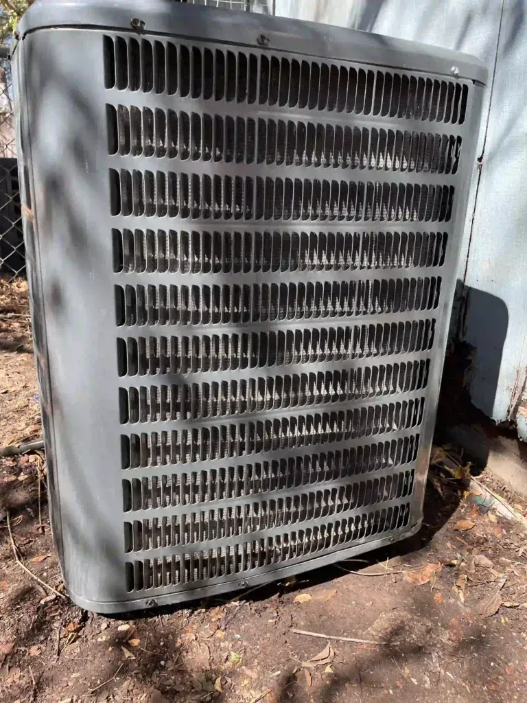 Gray air conditioning unit outdoors, with grilles.