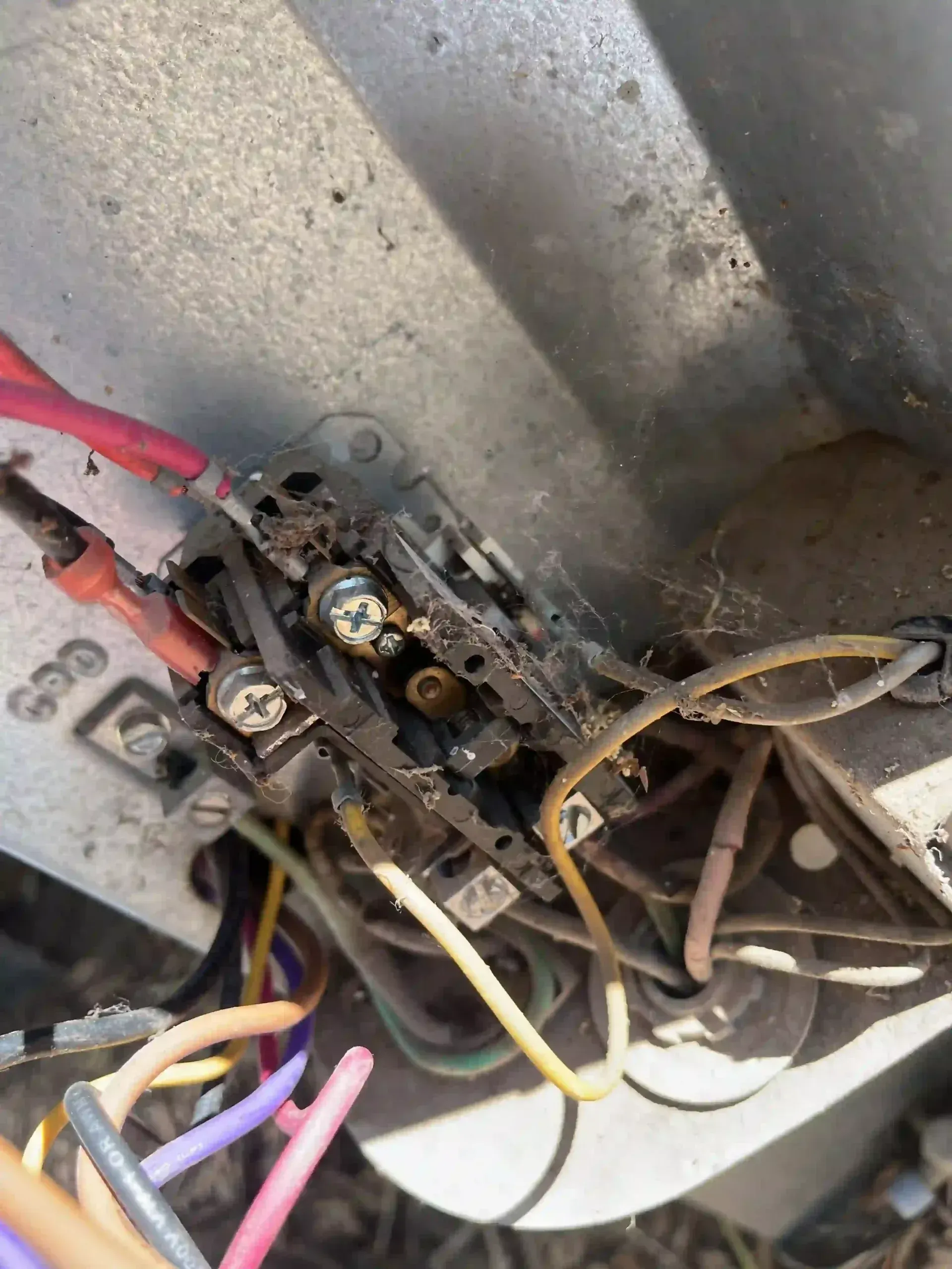 Damaged electrical wiring inside an outdoor AC unit. Burnt wires and connections are visible.