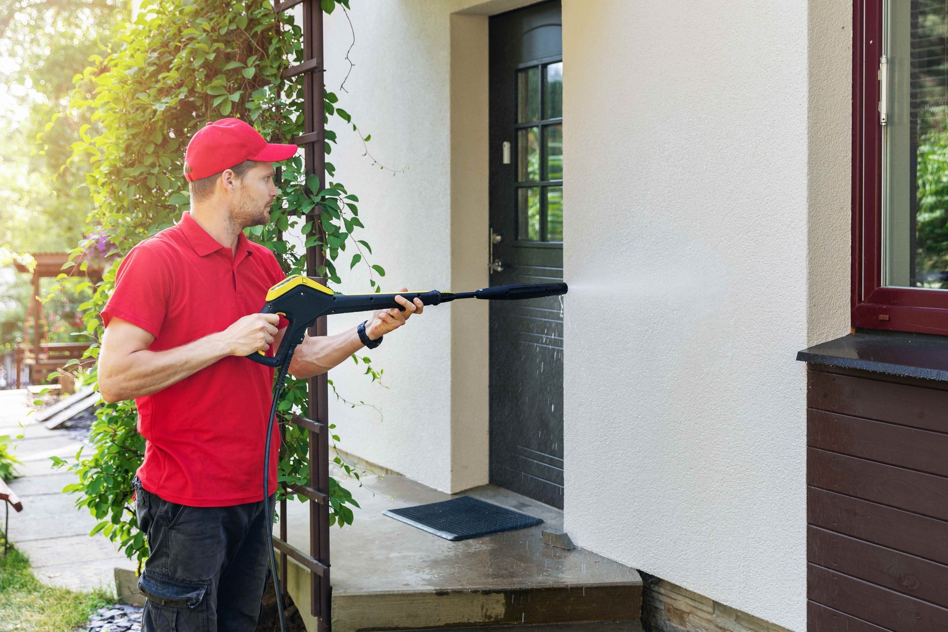 A man is cleaning the side of a house with a high pressure washer
