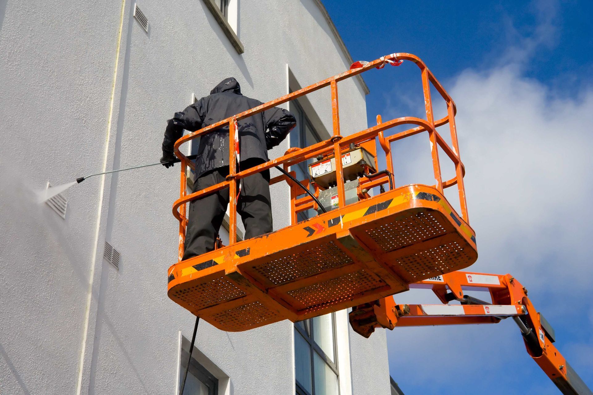 A man is cleaning a building with a high pressure washer