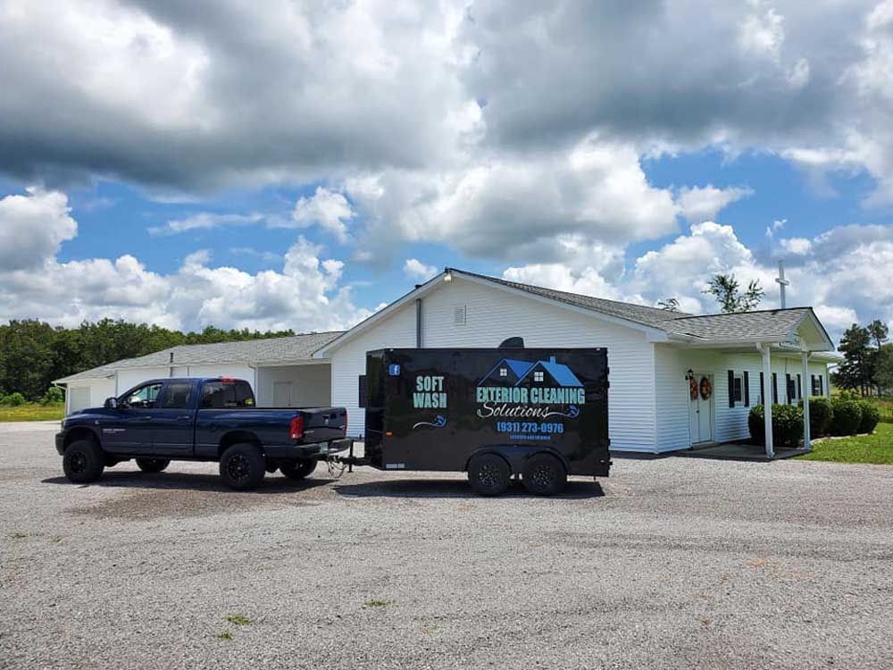 A truck and trailer are parked in front of a house.