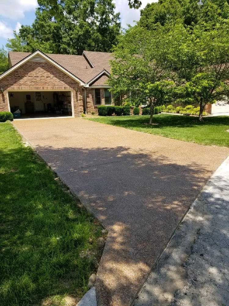 A driveway leading to a brick house with a garage.