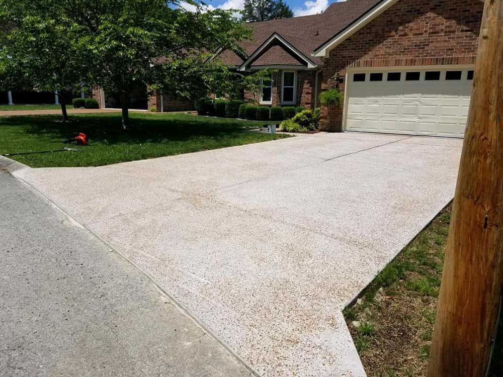 A driveway leading to a brick house with a garage.