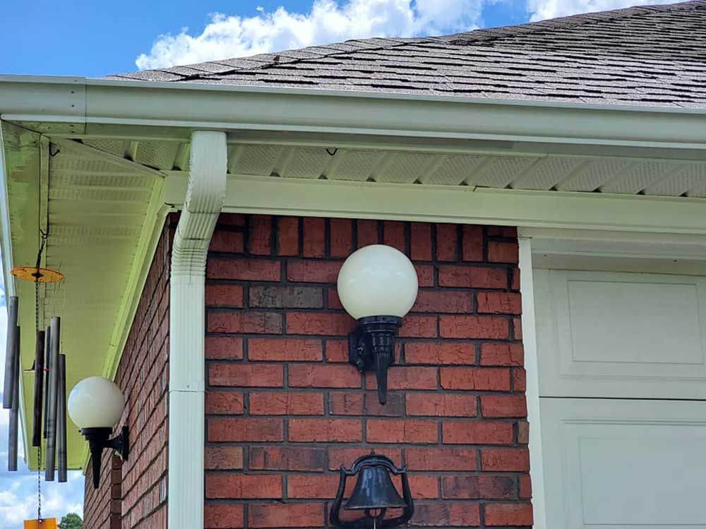 A brick house with a white garage door and two lights on the side of it.
