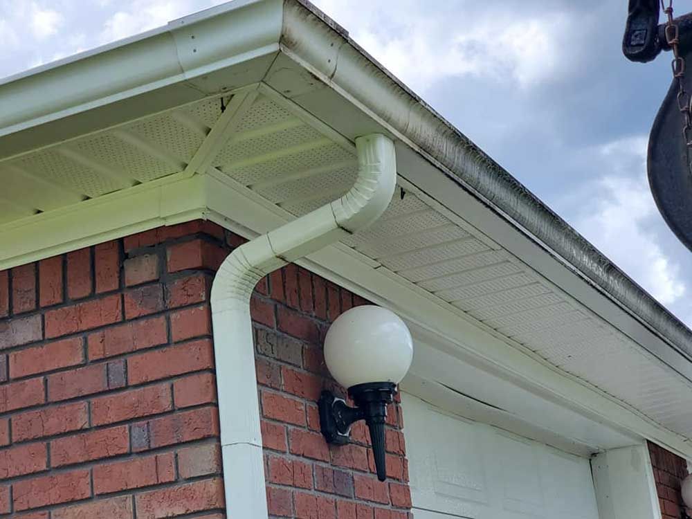 A brick house with a white gutter and a light on the side.
