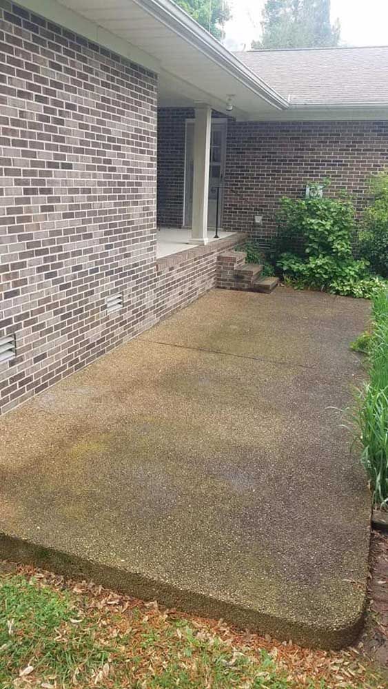 A brick house with a concrete patio in front of it.