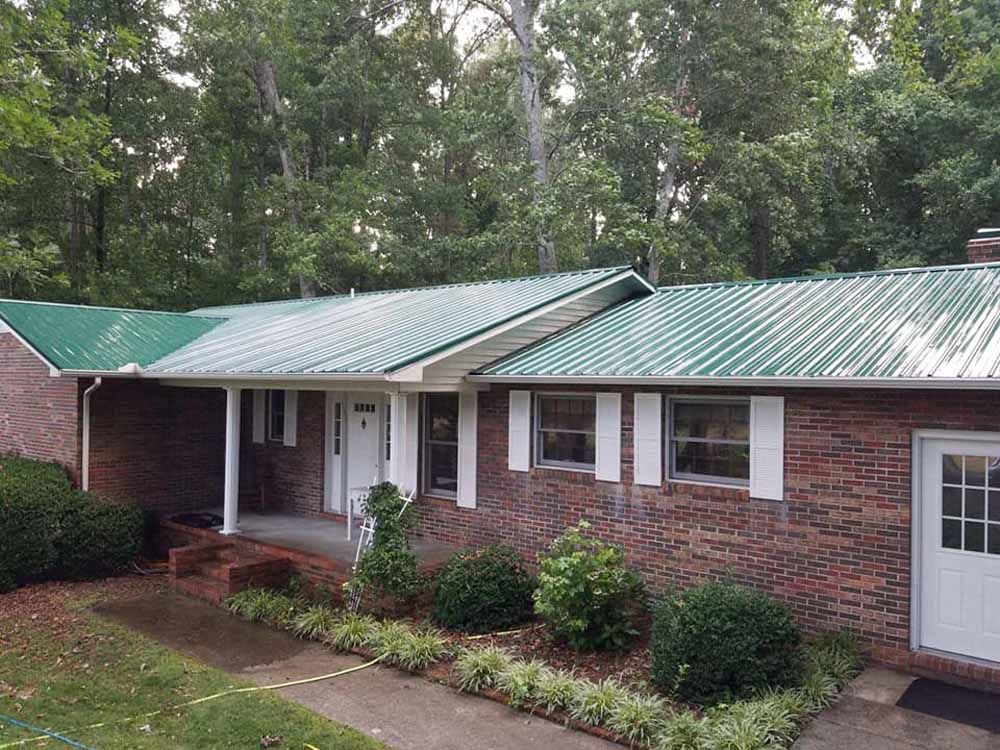 A brick house with a green metal roof and a porch.