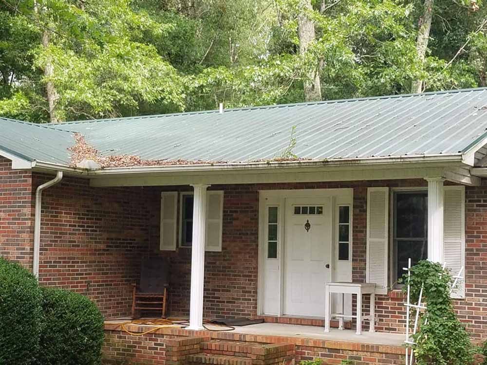A brick house with a metal roof and a porch with a rocking chair.