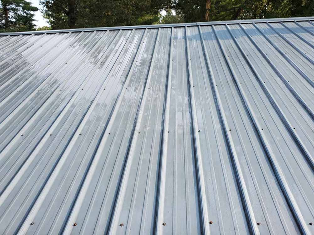A close up of a metal roof with trees in the background.