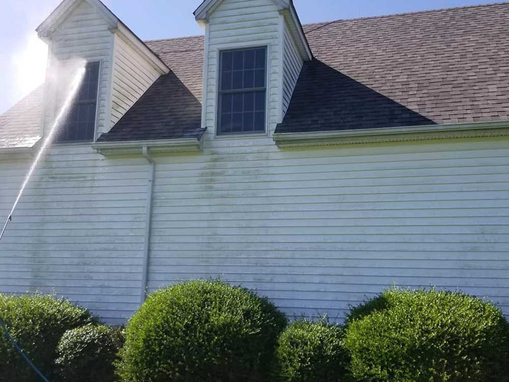 A house is being cleaned with a high pressure washer