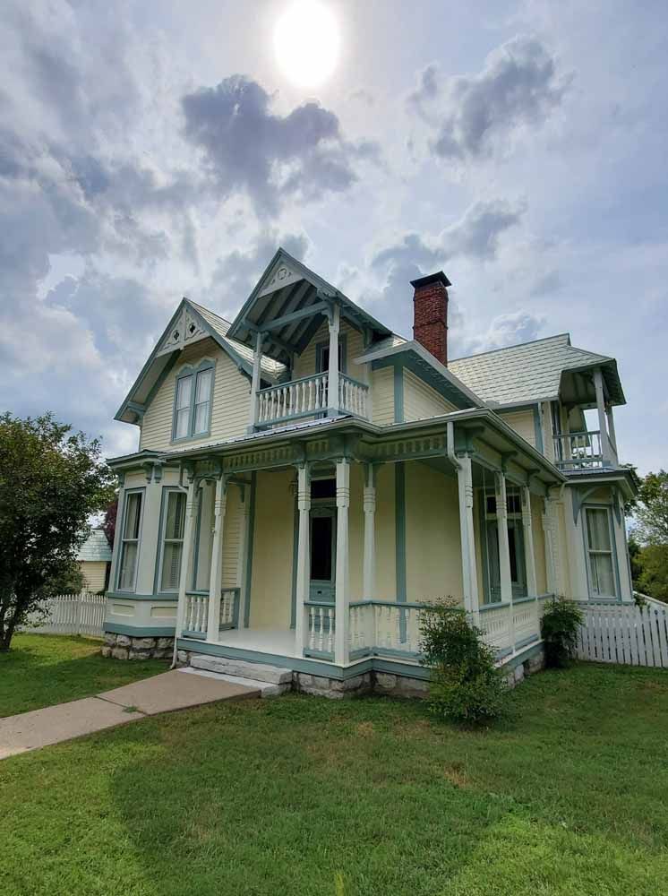 A large white house with a large porch and a brick chimney.