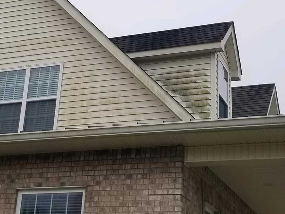 A brick house with a white siding and a black roof.