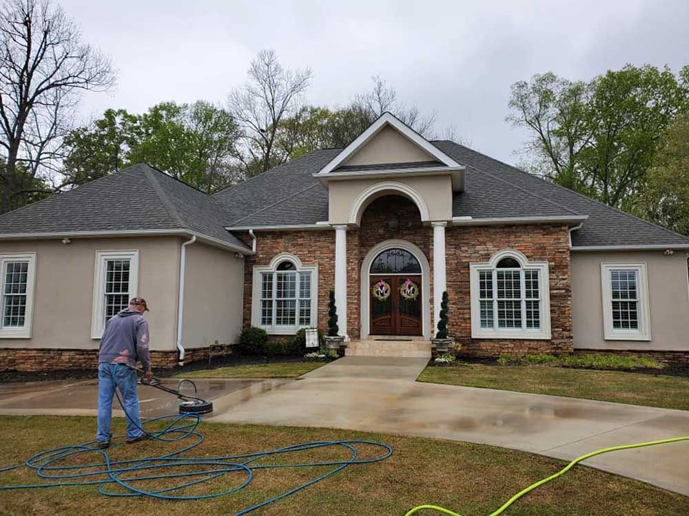 A man is cleaning the front of a large house.