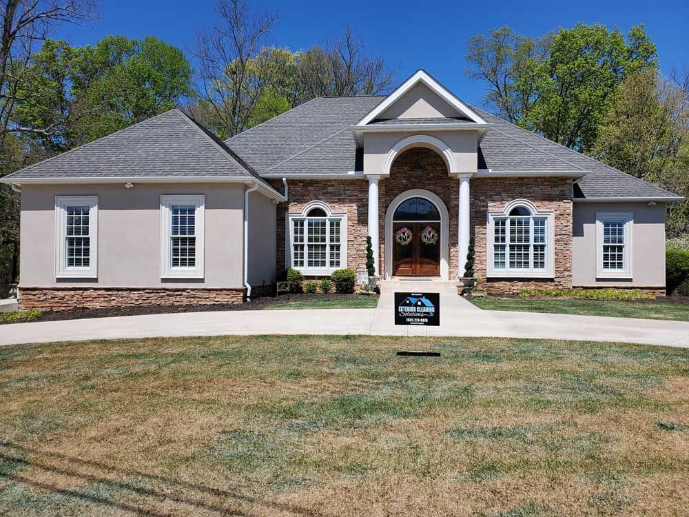 A large house with a gray roof and a sign in front of it.
