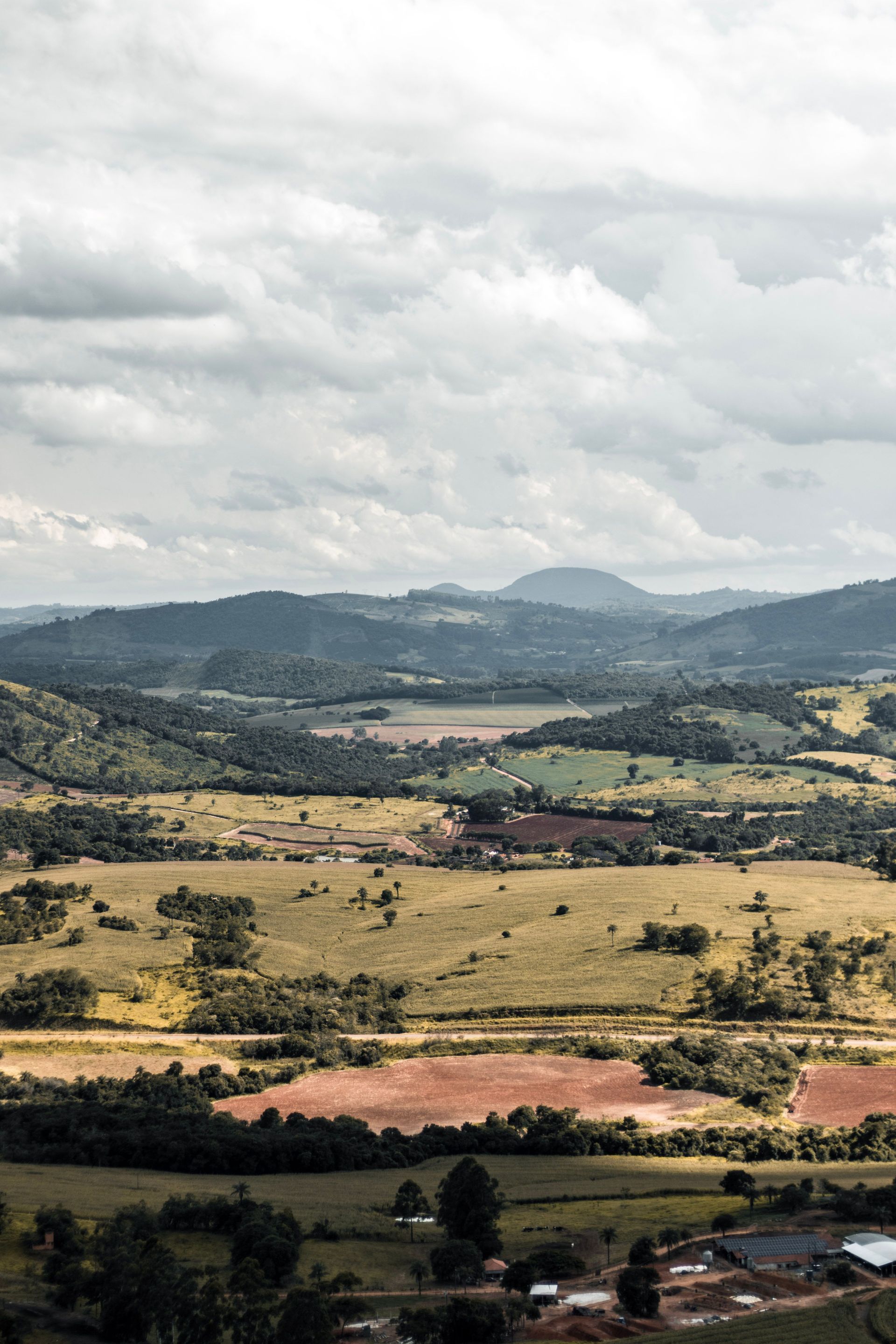 Wide rural valley with patchwork fields, distant hills, and cloudy sky