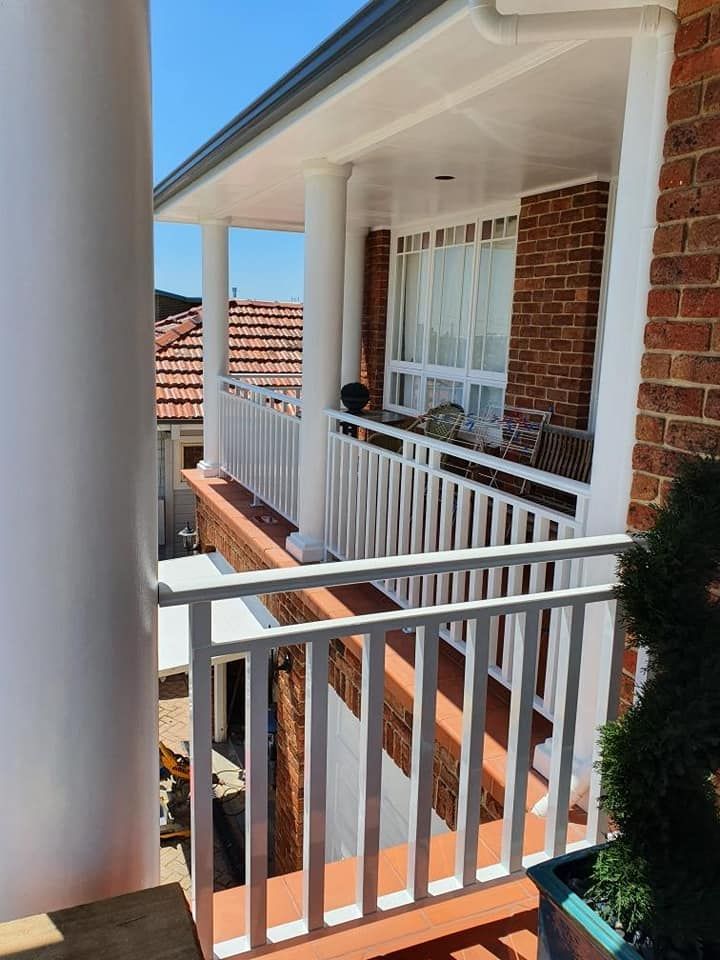 Balcony With A White Railing And A Brick Building — Decorative Aluminium Works In Central Coast, NSW