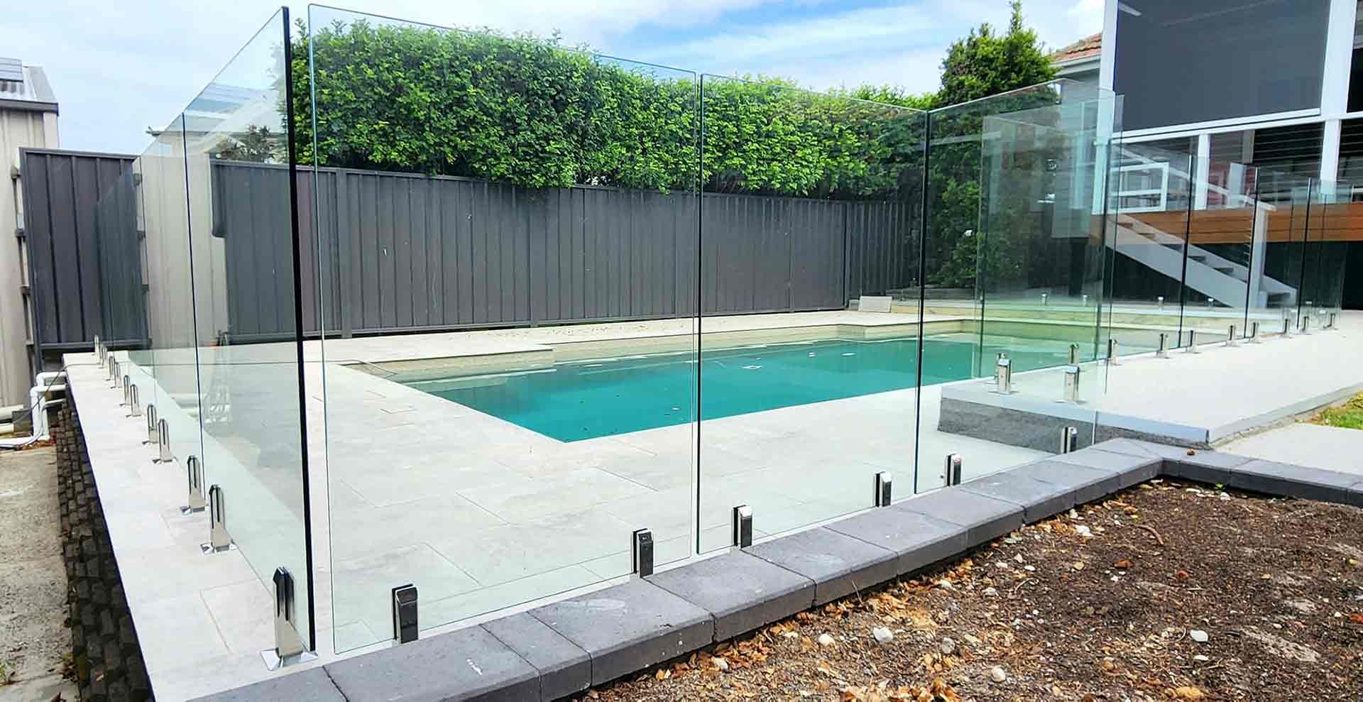 Swimming Pool With A Glass Fence Around It — Decorative Aluminium Works In Cardiff, NSW