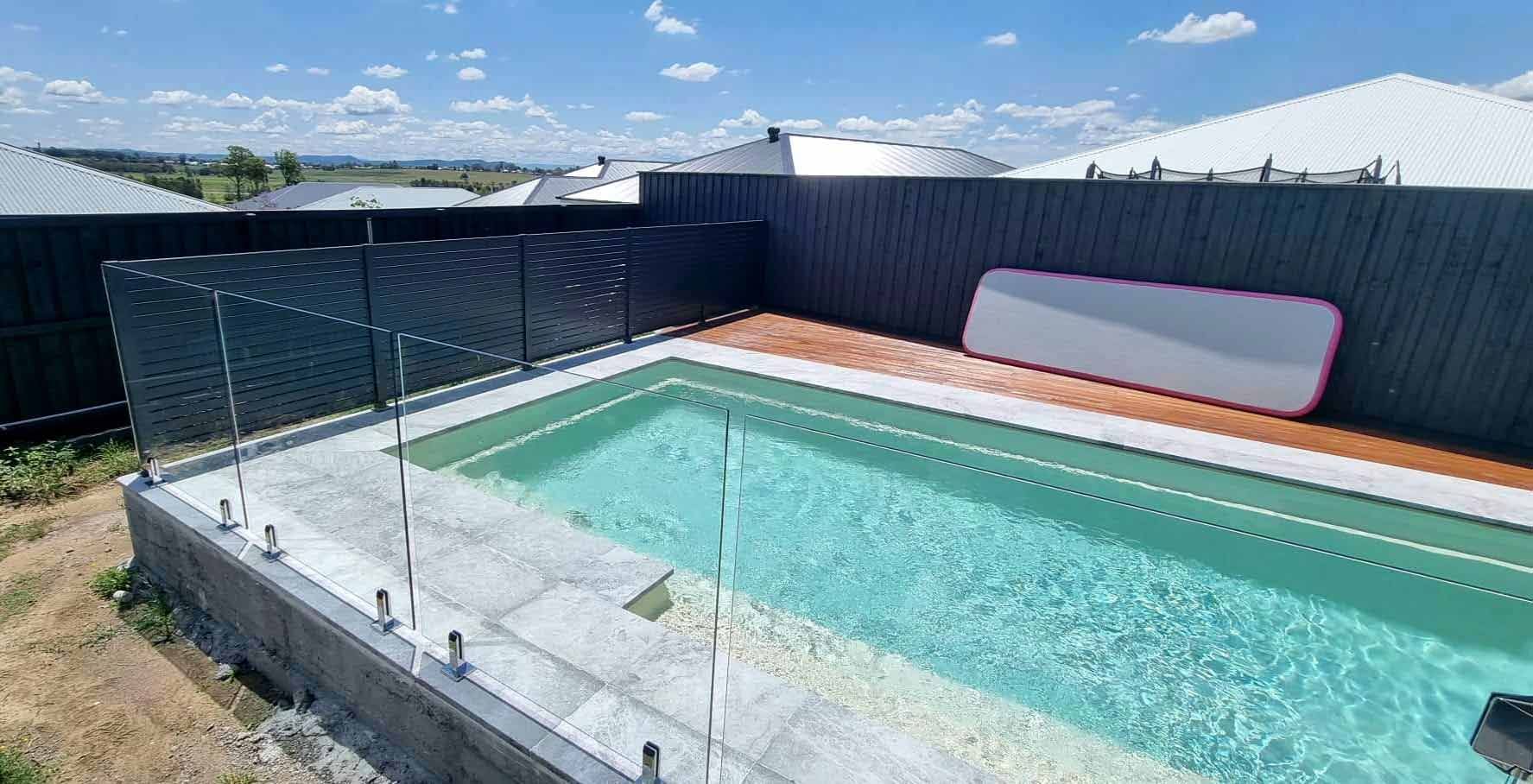 Large Swimming Pool Surrounded By A Fence And A Wooden Deck — Decorative Aluminium Works In Cardiff, NSW
