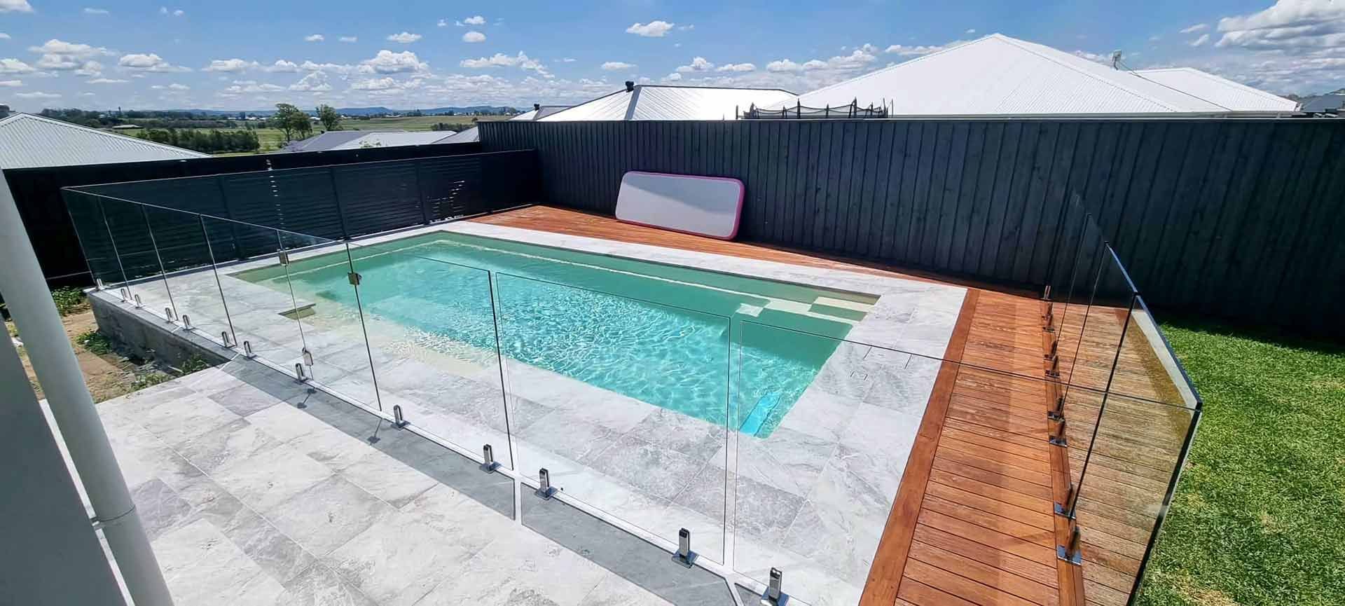 Large Swimming Pool With Glass And Aluminium Fence In The Backyard Of A House — Decorative Aluminium Works In Maitland, NSW