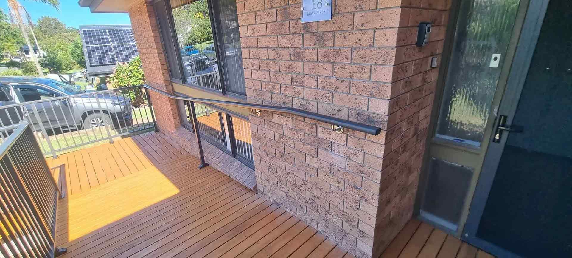 Brick Building With A Wooden Deck Stairs And A Safe Handrail — Decorative Aluminium Works In Cardiff, NSW