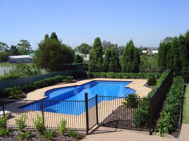 Large Swimming Pool With A Fence Around It — Decorative Aluminium Works In Newcastle, NSW