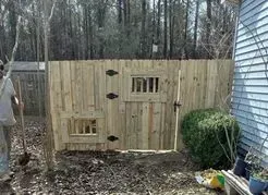 Wooden fence with gate, small windows, and a shrub.