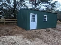 Green metal shed with a white door and window on dirt ground.