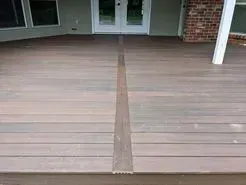 Brown composite deck with a dark brown strip down the center, leading to a doorway.