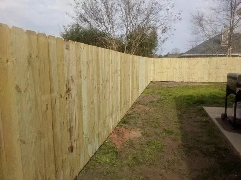 Wooden privacy fence in a grassy backyard.