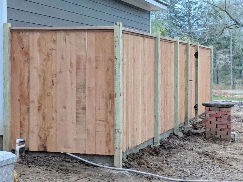 Wooden fence attached to a building's side, with a brick structure nearby.