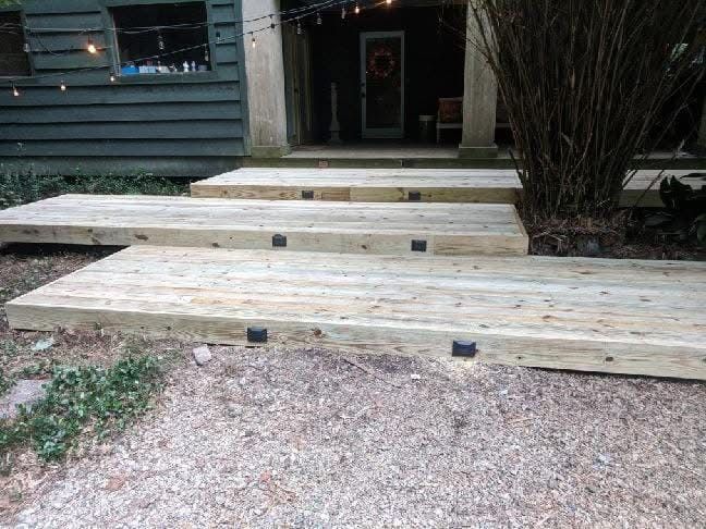 Wooden steps leading to a house entrance. Gravel pathway in front.