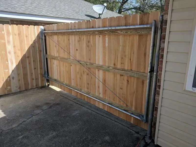 Wooden fence gate, metal frame, in a residential driveway.