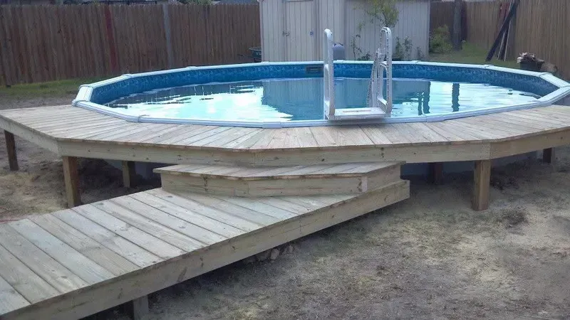 Above-ground pool with wooden deck and steps; outdoor setting.