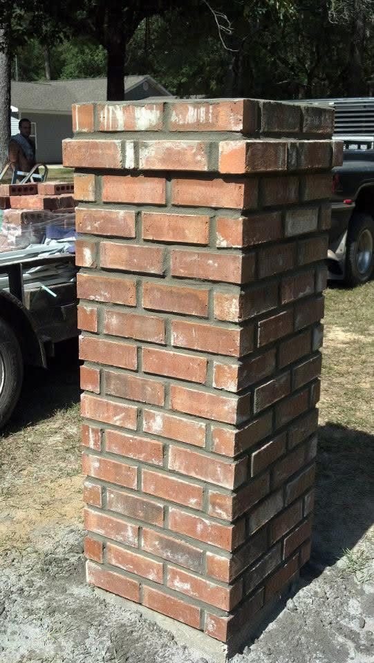 Brick pillar, reddish-brown bricks, built outdoors. Stacked brick layers, some mortar visible.