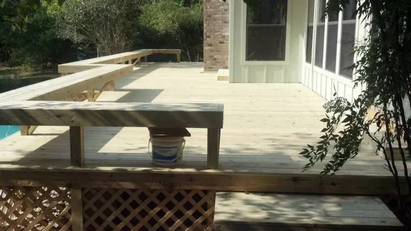 Wooden deck with lattice and built-in benches, adjacent to a screened porch.