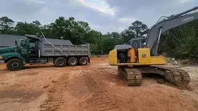 Excavator loading a dump truck with dirt at a construction site.
