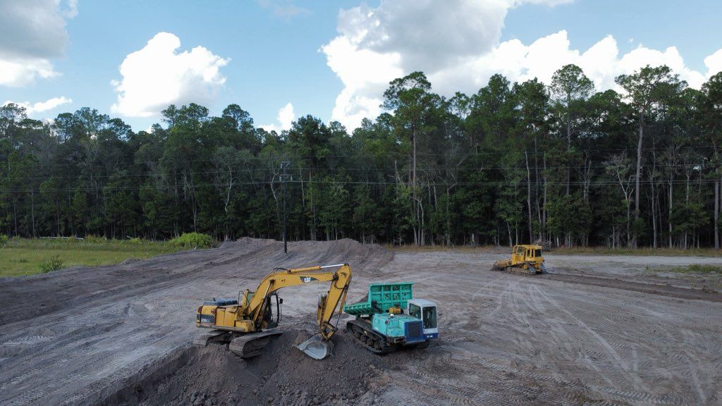 A large open-sided metal roof shelter supported by wooden posts in a grassy area with trees.
