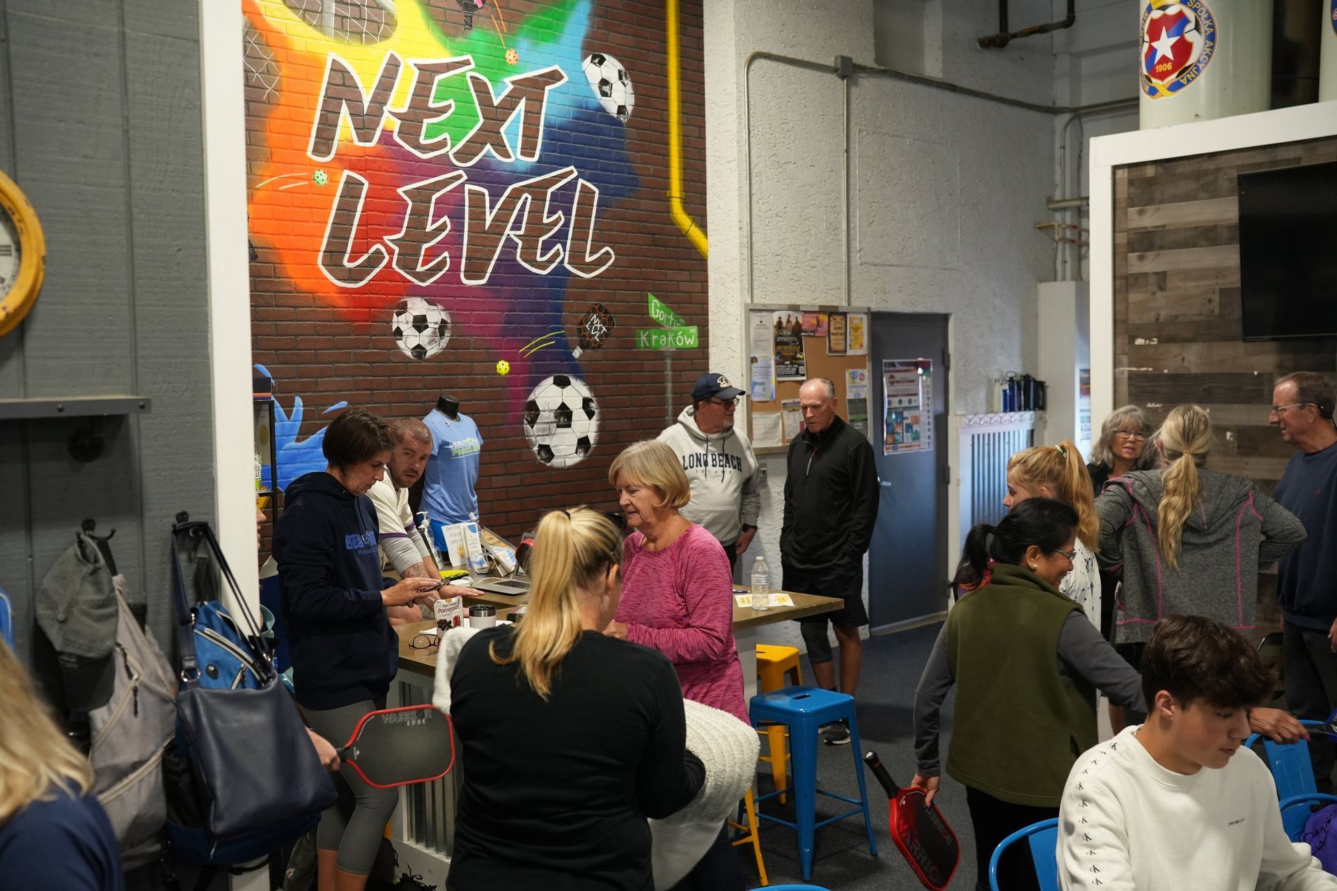 A group of people are sitting at tables in front of a wall that says `` next level ''.