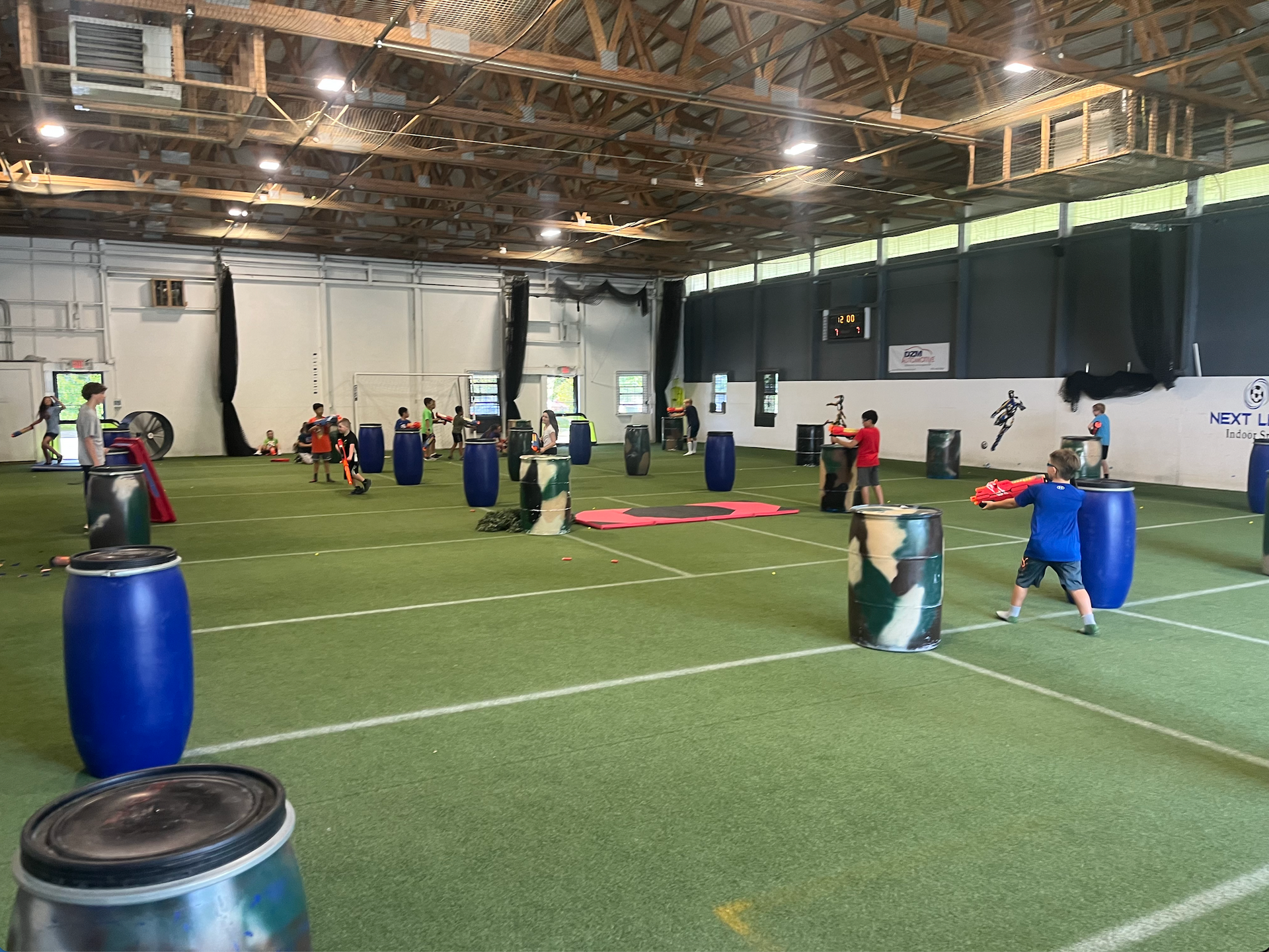 A group of people are playing a game of paintball in a large indoor arena.
