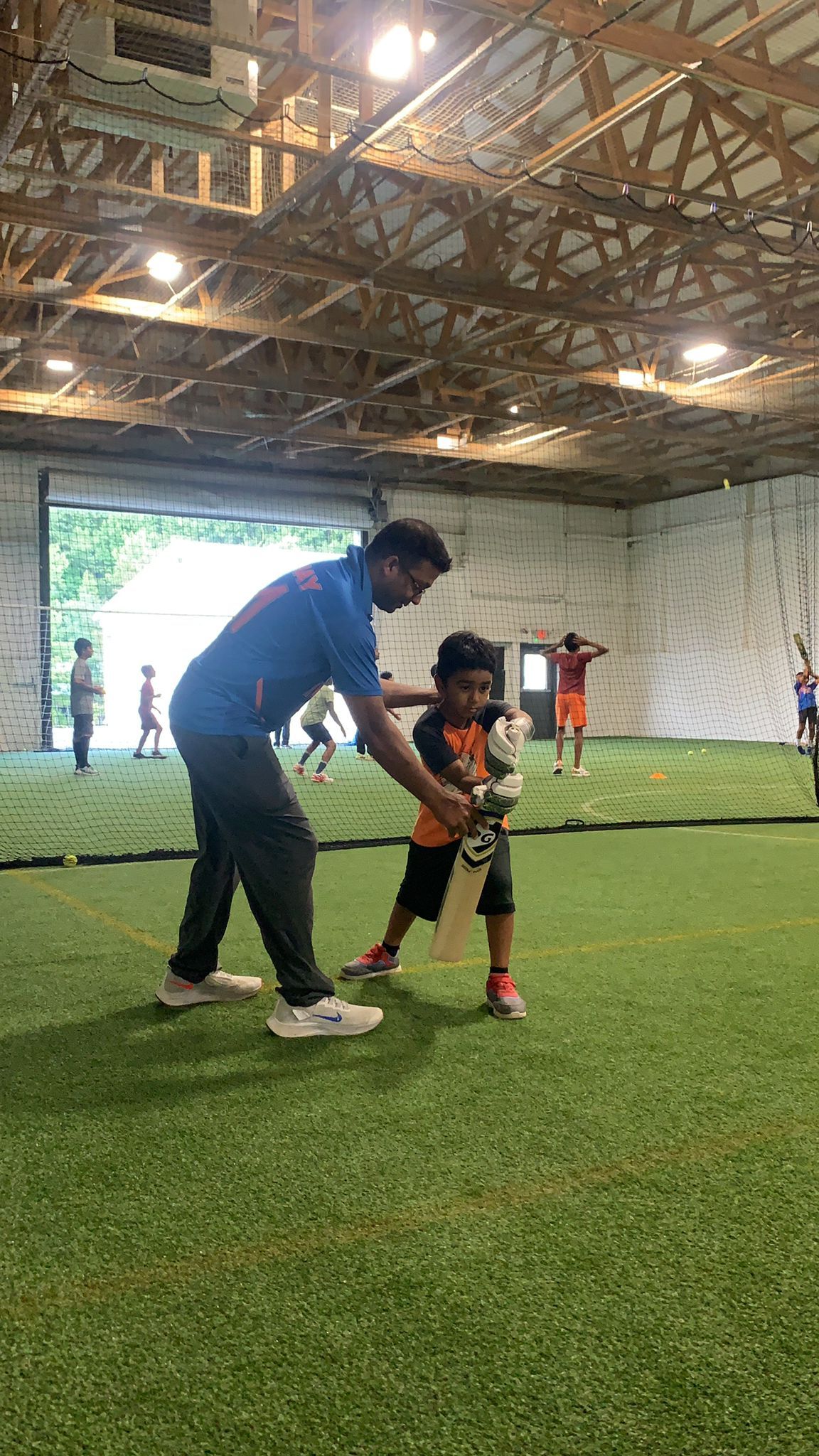 A group of children are playing soccer in an indoor stadium.