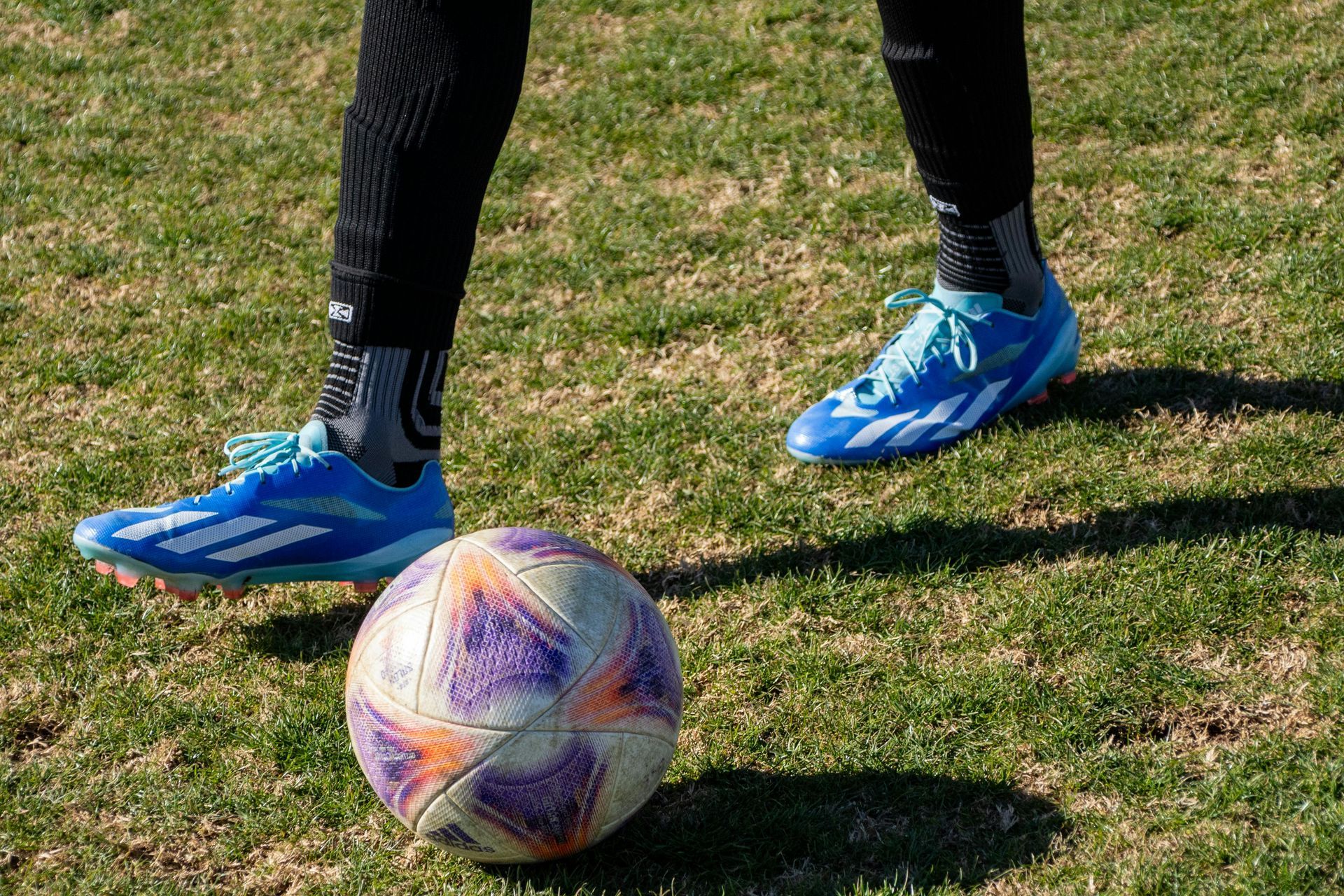A person is kicking a soccer ball on a field.