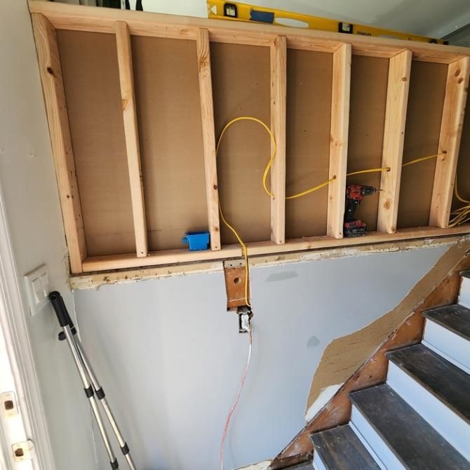 Wooden frame construction above stairs with electrical wiring and outlets.