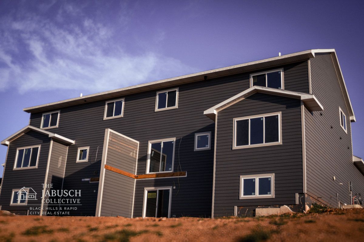 Dark gray multi-unit residential condo in Rapid City with multiple windows under blue sky.