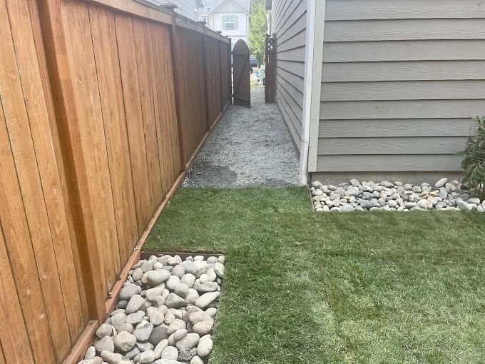 Green lawn with red bush, garage, and a white car on a sunny day.