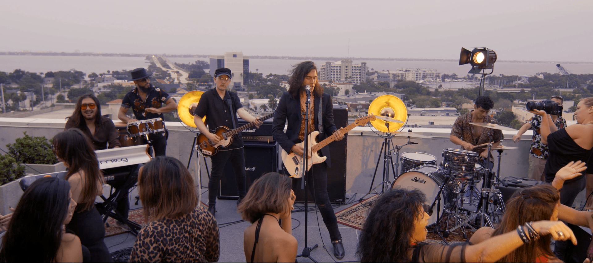 A group of people are watching a band perform on a rooftop.