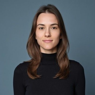 La donna indossa un dolcevita nero e sorride alla telecamera.